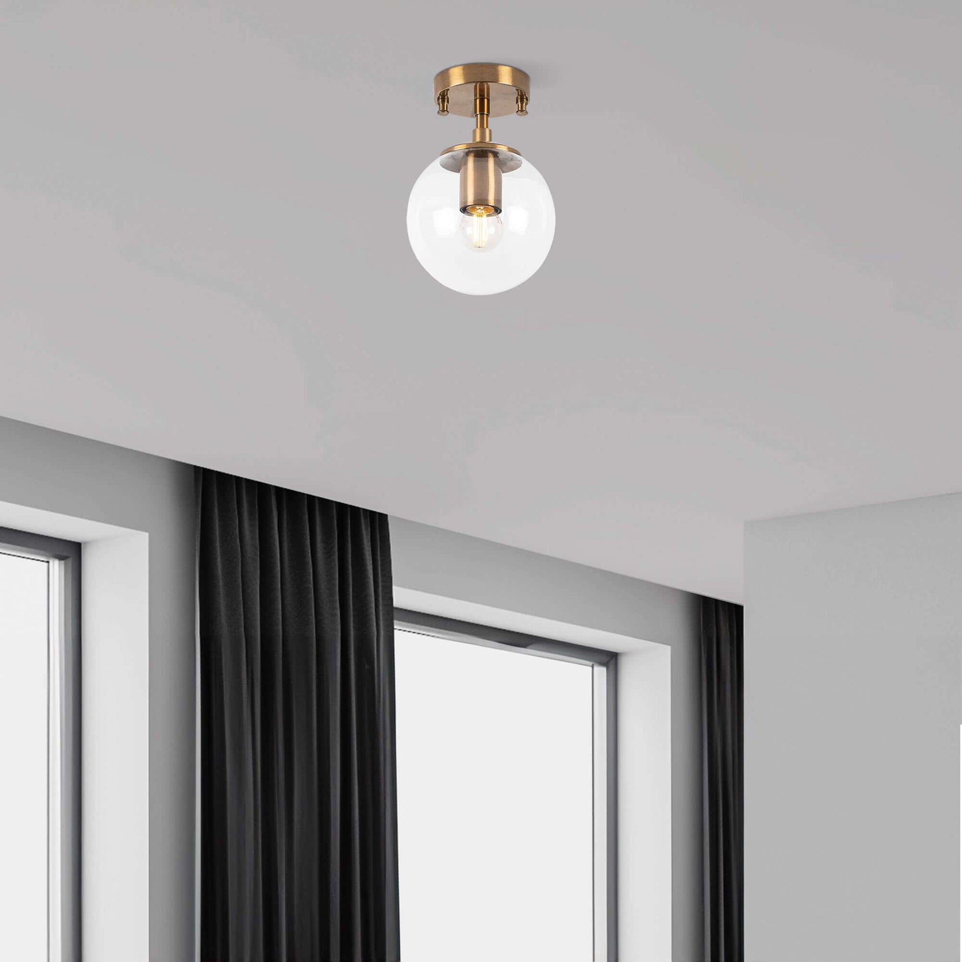 Clear glass globe ceiling light with brass finish, modern simplicity meets vintage charm.