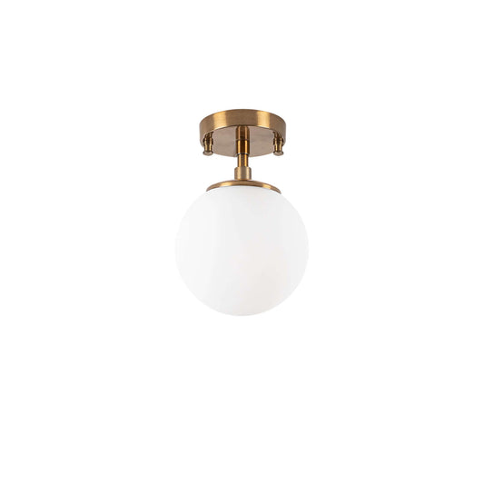 Frosted glass globe ceiling light with brass finish emitting soft glow.