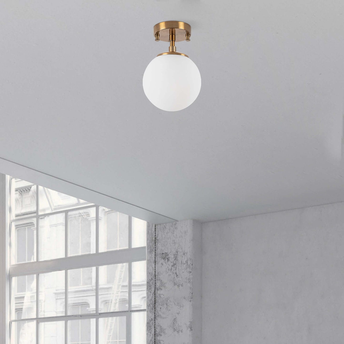 Frosted glass globe ceiling light with brass finish emitting soft glow.